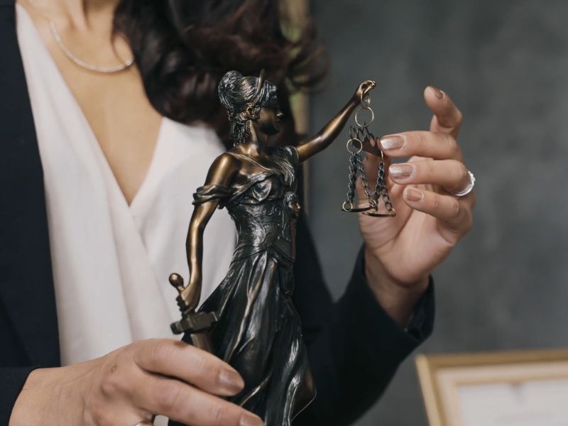 advokatica drži advokatsku figuru u ruci